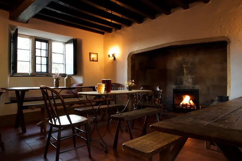 Interior de hotel con chimenea, luz cálida y mesas de madera; un lugar perfecto para pensar tras una travesía.