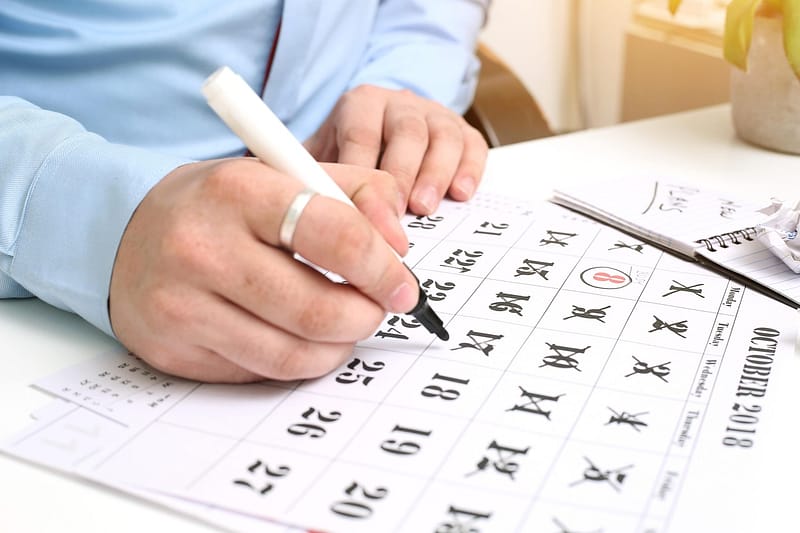 Forecast hotelero: mano marcando fechas en un calendario de planificación mensual