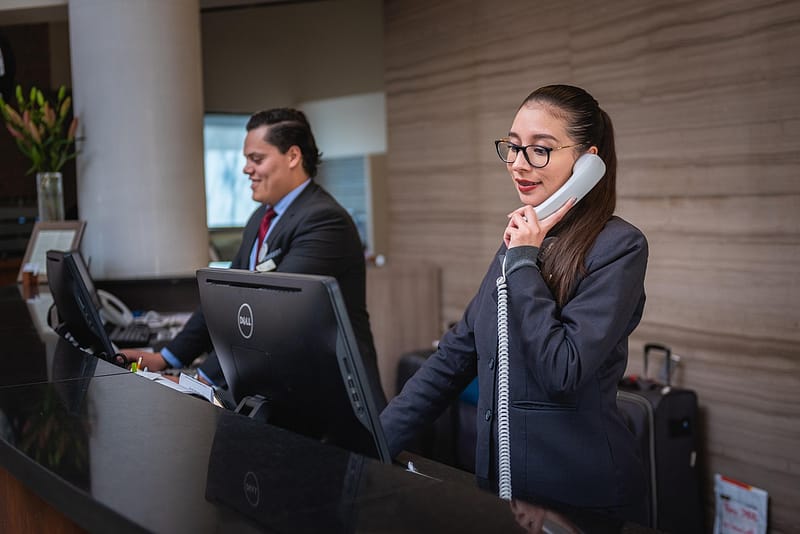Recepción de hotel atendiendo una llamada: cómo reducir las comisiones de Booking sin perder reservas