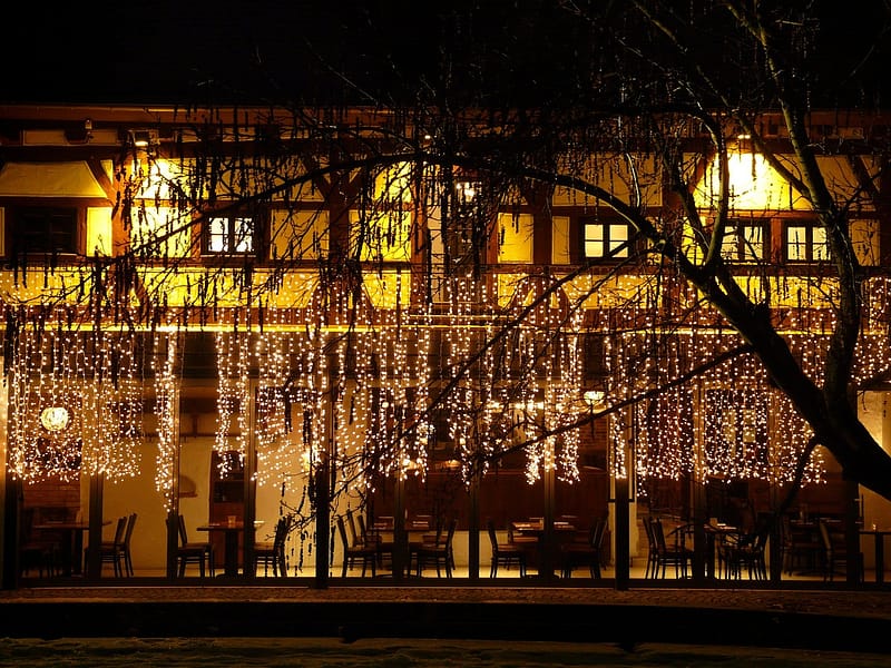 Fachada de un hotel independiente iluminada al anochecer con la terraza abierta